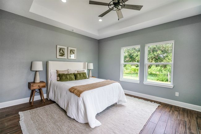Bedroom with a raised ceiling, baseboards, recessed lighting, wood finished floors, and ceiling fan | Image 15