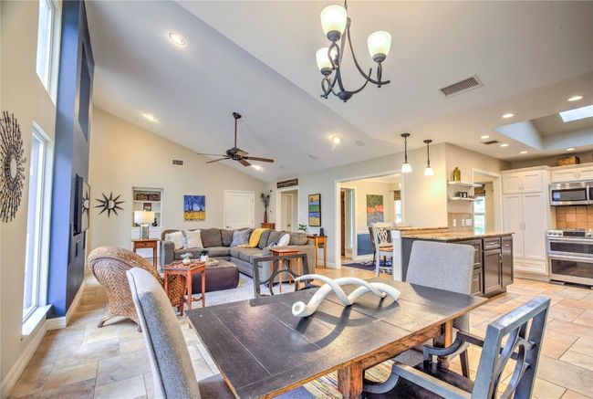 Living room from behind kitchen dining space featuring stone tile floors, and recessed lighting | Image 14