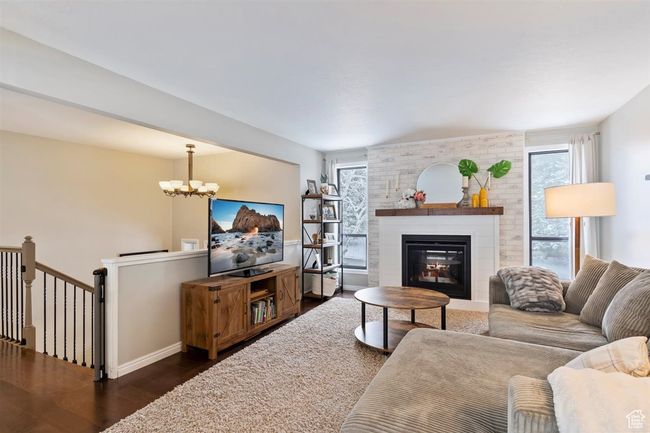 Living room with plenty of natural light, dark wood-style floors, a chandelier, and a brick fireplace | Image 10