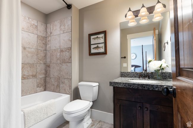 Full bath with tile patterned flooring, vanity, toilet, shower / bath combo with shower curtain, and baseboards | Image 21