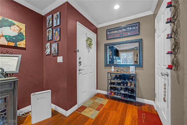 Entryway with baseboards, a textured wall, wood finished floors, and ornamental molding | Image 7