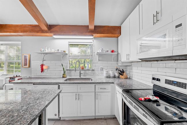 Kitchen with a sink, a wealth of natural light, open shelves, and white appliances | Image 5