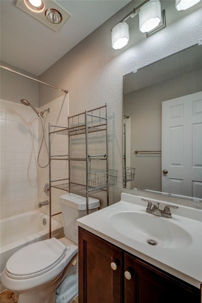 Bathroom featuring toilet, bathing tub / shower combination, vanity, and a textured wall | Image 22