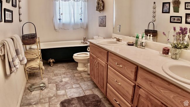 Full bathroom featuring a bath, stone finish flooring, toilet, a sink, and double vanity | Image 68