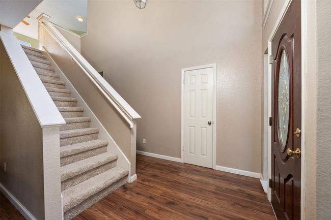 Foyer entrance featuring baseboards, a towering ceiling, wood finished floors, and stairs | Image 16