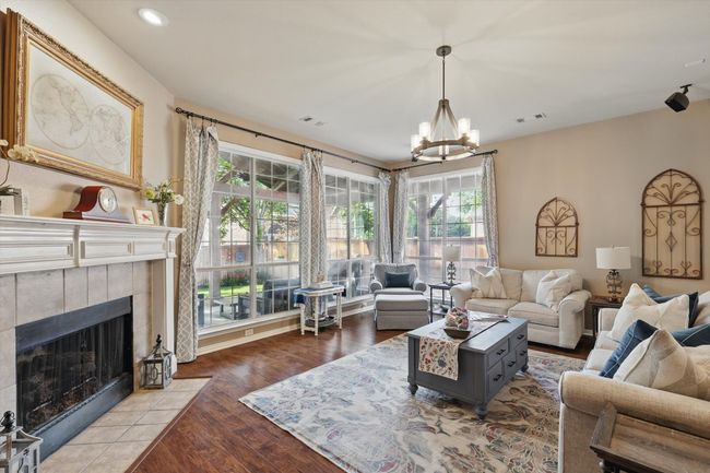 Living area with a chandelier, plenty of natural light, a fireplace, wood finished floors, and recessed lighting | Image 6