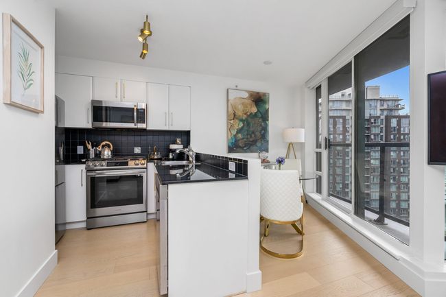 Kitchen featuring appliances with stainless steel finishes, dark countertops, light wood-style flooring, and backsplash | Image 9