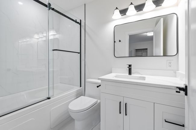Full bath featuring vanity, toilet, and combined bath / shower with glass door | Image 15