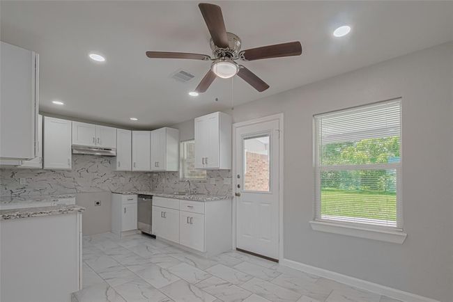 The dining area sits beside a large window overlooking the backyard, offering a charming space to gather with views of greenery. | Image 13