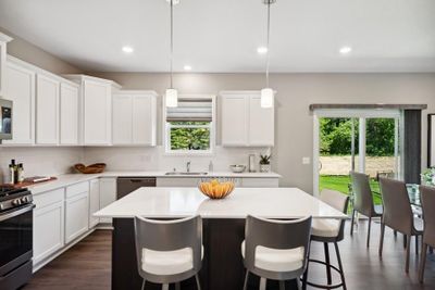 This spacious kitchen features a large center island, quartz countertops, recessed lighting, LVP wood floors, stainless appliances and more! (Model photo) | Image 2