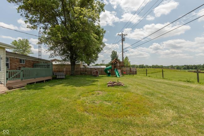 fenced backyard with a playground and a wooden deck | Image 22