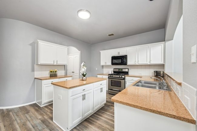 Kitchen with a sink, black microwave, wood finished floors, and stainless steel range with gas cooktop | Image 14