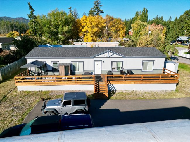 View of front of home with a wooden deck, fence private yard, and roof with shingles | Image 26