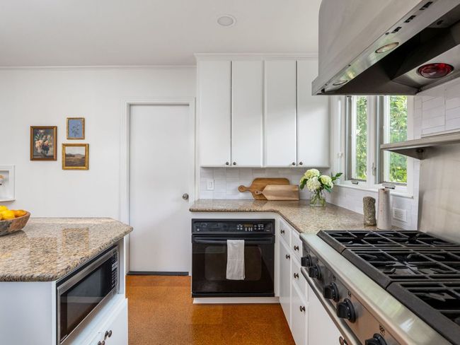 Kitchen with stainless steel refrigerator, kitchen island, & backsplash. | Image 13