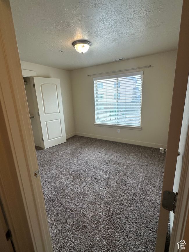 Unfurnished bedroom featuring a textured ceiling, carpet floors, and baseboards | Image 14