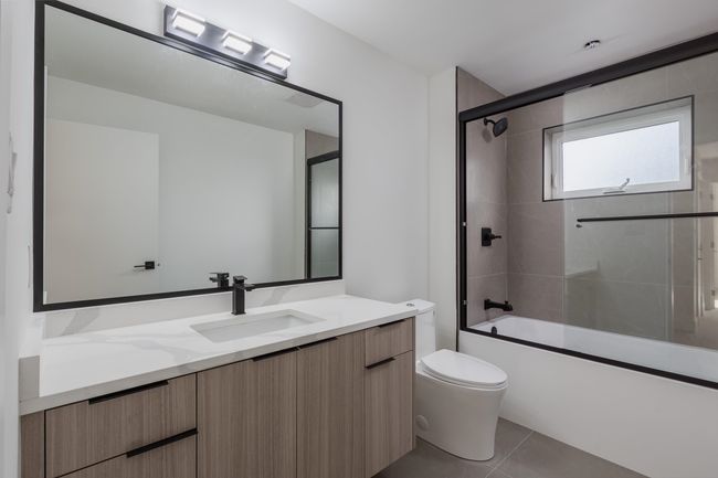 Bathroom featuring shower / bath combination with glass door, toilet, vanity, and tile patterned flooring | Image 30