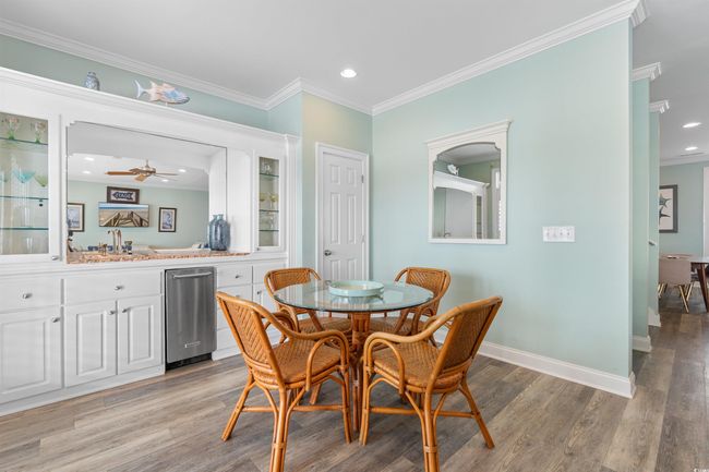 Dining space featuring bar with sink, light wood-style floors, crown molding | Image 22
