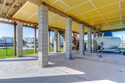 This is a spacious covered outdoor area with sturdy columns, ideal for parking or storage, featuring high ceilings and a boat on a trailer. | Image 2