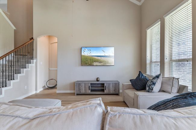 Living room featuring arched walkways, wood finished floors, stairway, a high ceiling, and baseboards | Image 8