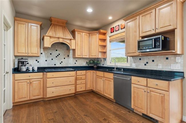 Kitchen featuring light brown cabinetry, custom exhaust hood, stainless steel appliances, and a sink | Image 16