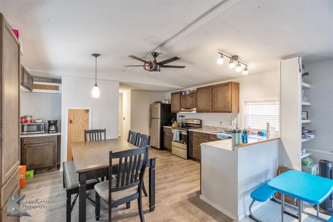 Kitchen featuring stainless steel appliances, light countertops, vaulted ceiling, and light wood finished floors | Image 20