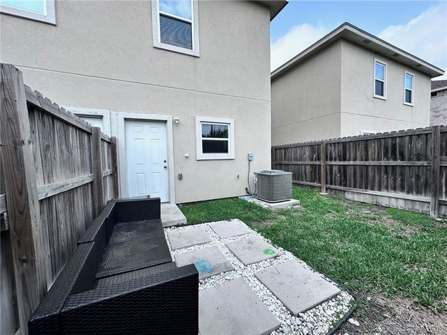 Rear view of house featuring a fenced backyard, stucco siding, central AC unit, and a lawn | Image 12