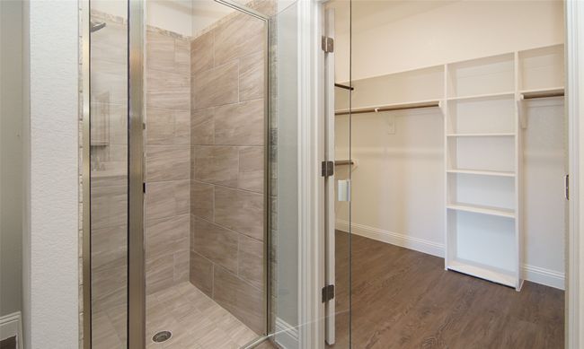 Bathroom featuring a stall shower, a spacious closet, and wood finished floors | Image 5