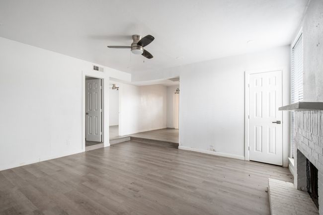 Unfurnished living room featuring ceiling fan, light hardwood / wood-style flooring, and a brick fireplace | Image 6