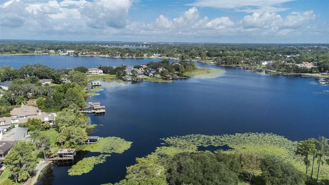 This stunning aerial view captures the serene beauty of Windermere just outside the gates of Keene’s Pointe. The expansive lake—part of the famed Butler Chain of Lakes—stretches across the horizon, flanked by luxury waterfront estates with private docks nestled among lush, mature trees. The scene reflects the quintessential Windermere lifestyle: peaceful, upscale, and deeply connected to nature. It’s easy to see why this area remains one of Central Florida’s most desirable communities, offering a rare blend of exclusivity and lakefront living just minutes from world-class golf and amenities. | Image 37