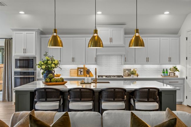 Kitchen featuring light countertops, a breakfast bar, tasteful backsplash, and recessed lighting | Image 11