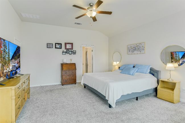 Bedroom with light colored carpet, baseboards, lofted ceiling, and ceiling fan | Image 19