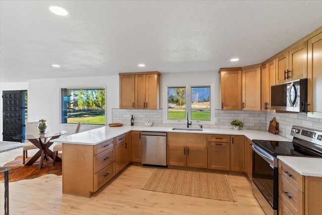 Kitchen with light hardwood / wood-style flooring, sink, decorative backsplash, kitchen peninsula, and appliances with stainless steel finishes | Image 17