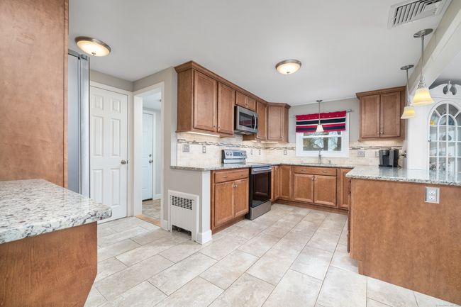 Off kitchen is 1/2 bath/powder room, enclosed mudroom off garage and door to back yard | Image 10