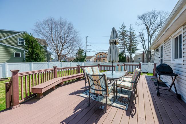 Wooden deck with a fenced backyard, a grill, and outdoor dining space | Image 17