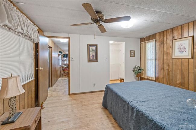 Bedroom featuring wooden walls, light wood finished floors, and a ceiling fan | Image 13