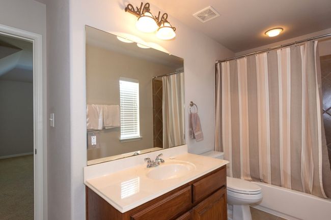 Bathroom with toilet, shower / tub combo, vanity, and visible vents | Image 18