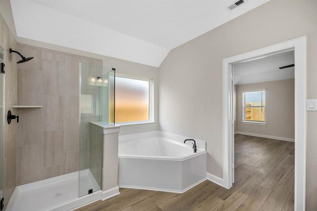 Welcome to the en-suite bathroom, featuring a chic vanity with ample storage space and a separate tub and shower combo for added luxury. Whether indulging in a soothing bath or refreshing shower, this well-appointed space offers the perfect retreat after a long day. | Image 6