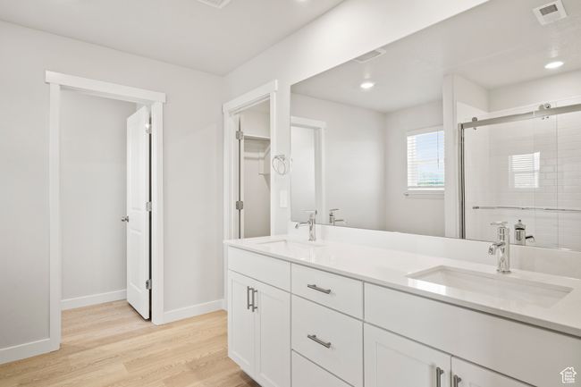 Full bathroom featuring double vanity, wood finished floors, a shower stall, baseboards, and recessed lighting | Image 33