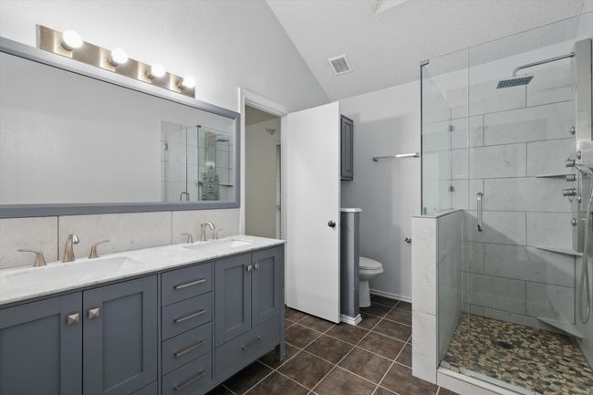 Bathroom with vaulted ceiling, a shower stall, double vanity, and tile patterned flooring | Image 19