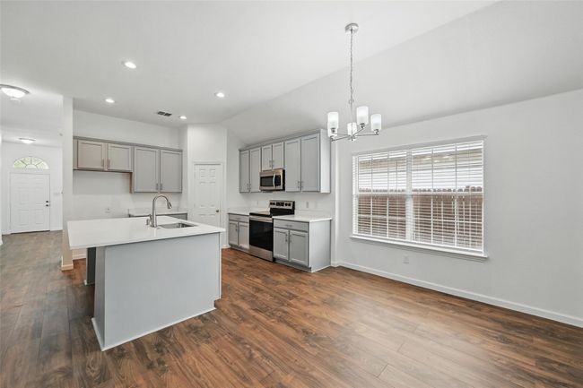 Kitchen with stainless steel appliances, gray cabinetry, a sink, a chandelier, and baseboards | Image 16