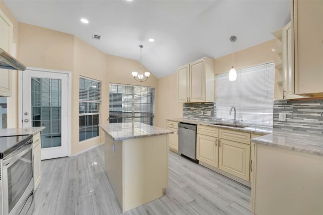 Kitchen featuring appliances with stainless steel finishes, a kitchen island, sink, backsplash, and cream cabinetry | Image 7