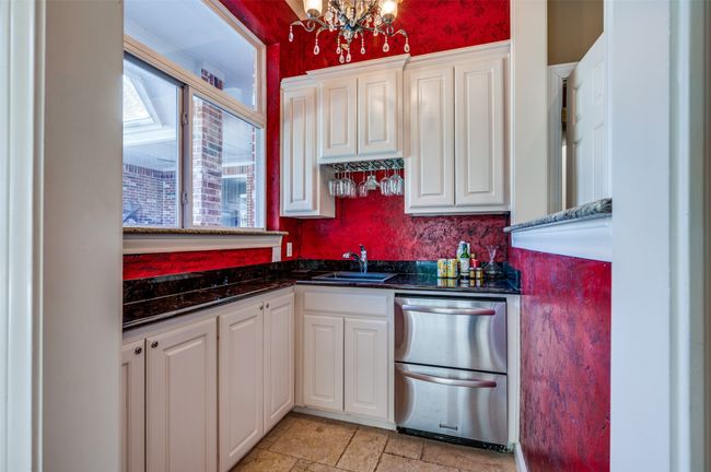 Kitchen with a sink, stainless steel dishwasher, a chandelier, and white cabinetry | Image 26