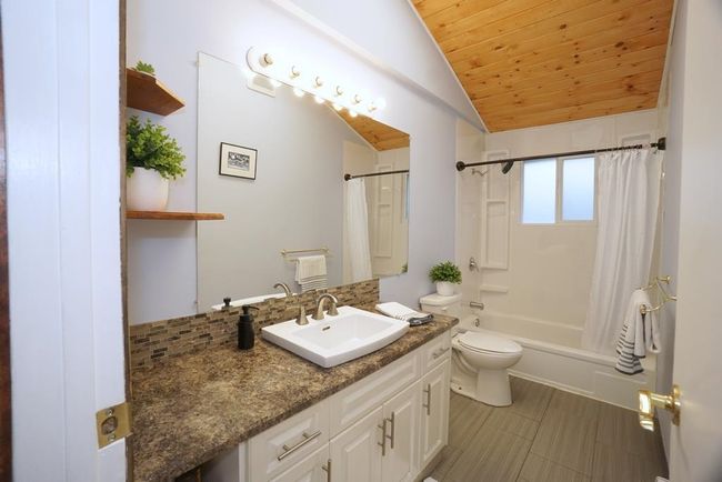 Full bath featuring vanity, wooden ceiling, shower / bath combo, lofted ceiling, and decorative backsplash | Image 10