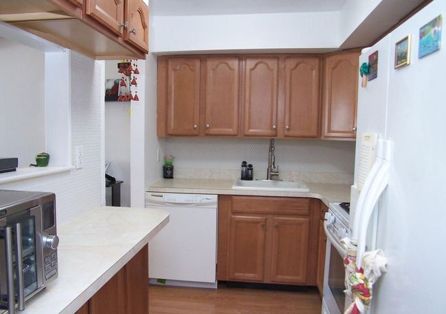 Kitchen with white appliances, light countertops, a sink, and decorative backsplash | Image 16