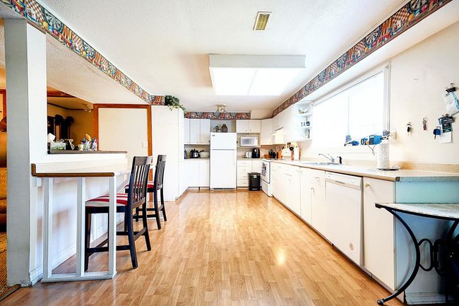 Kitchen featuring white appliances, light wood finished floors, a sink, and white cabinets | Image 12