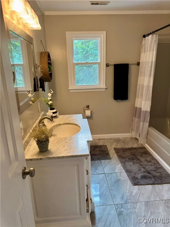Bathroom with vanity, healthy amount of natural light, crown molding, shower / bath combo with shower curtain, and baseboards | Image 10