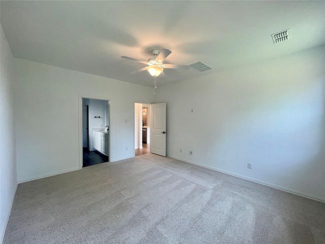 Unfurnished bedroom featuring carpet floors, ceiling fan, and connected bathroom | Image 12