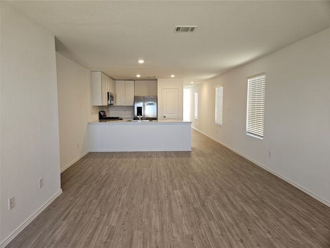 Unfurnished living room featuring dark wood-style floors, visible vents, recessed lighting, and baseboards | Image 5