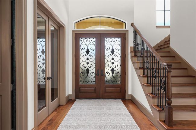 Another view of the double iron inset doors and beautiful iron work on the stairs. The office is located through the double glass doors to the left. | Image 8
