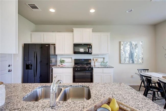 Kitchen with black appliances, light stone counters, white cabinetry, and recessed lighting | Image 8